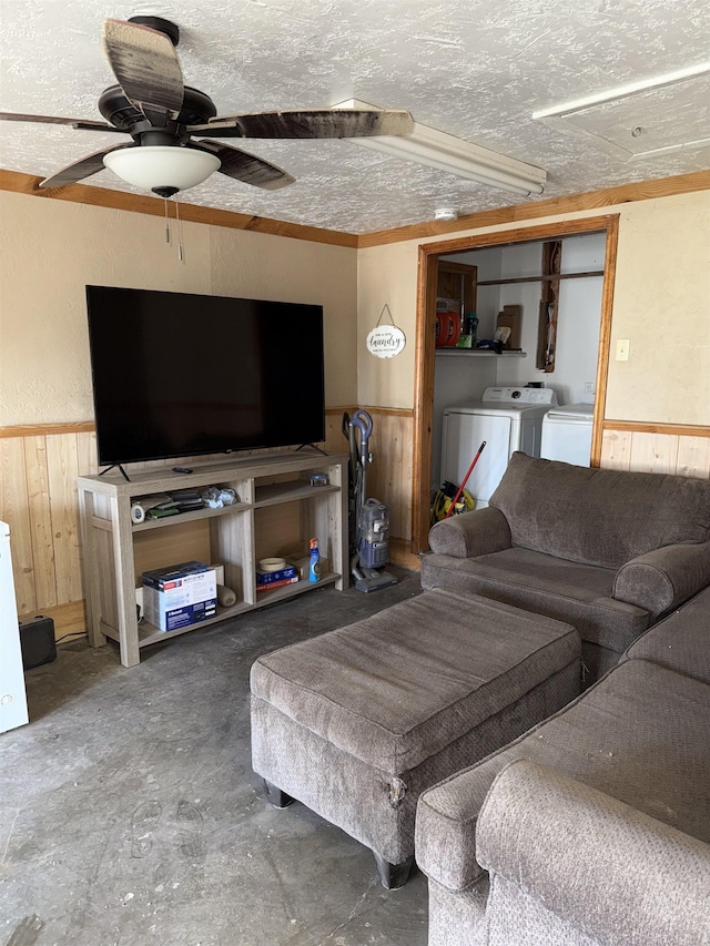 living room with a wainscoted wall, independent washer and dryer, unfinished concrete flooring, a textured ceiling, and wooden walls