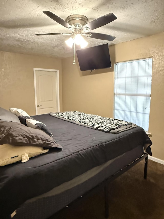 carpeted bedroom featuring a textured ceiling and ceiling fan