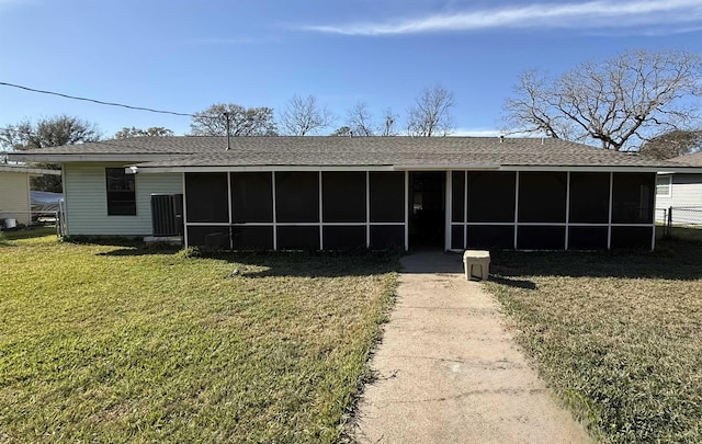 view of front of house with roof with shingles, a front yard, and a sunroom