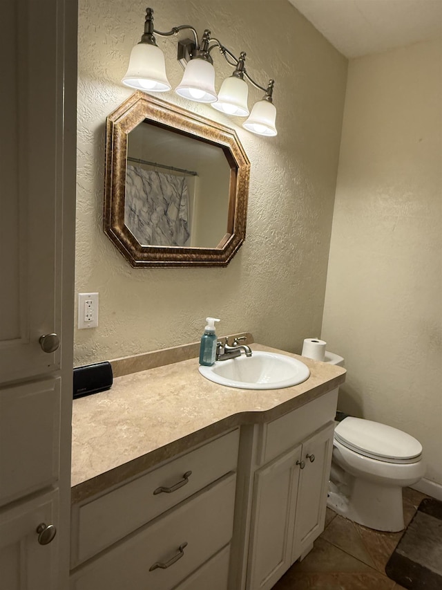 bathroom featuring tile patterned flooring, toilet, vanity, and a textured wall