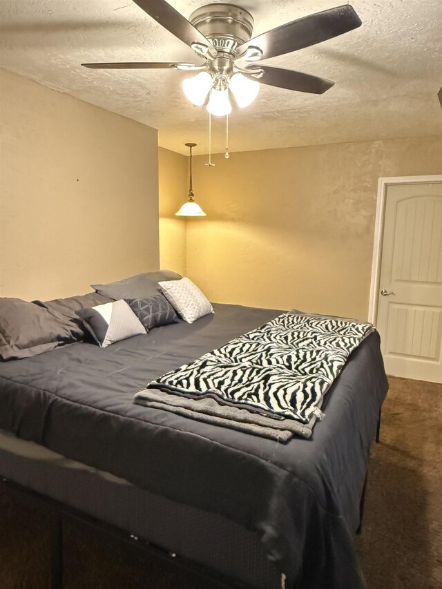 carpeted bedroom with a ceiling fan and a textured ceiling