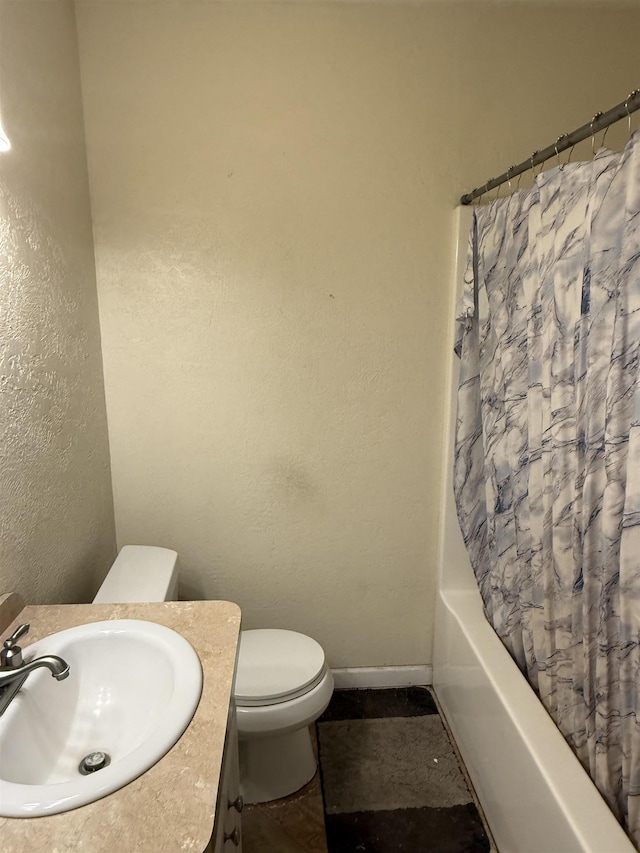 full bathroom with vanity, baseboards, shower / bath combo, toilet, and a textured wall