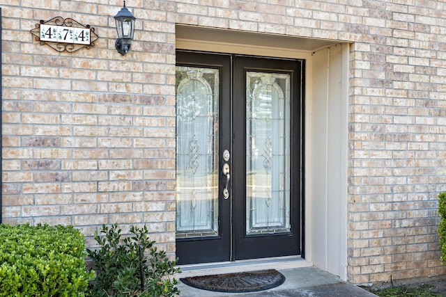 doorway to property featuring brick siding and french doors