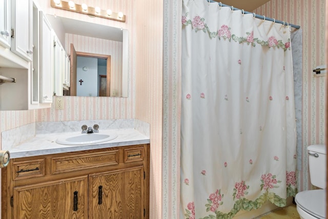 bathroom with wallpapered walls, toilet, vanity, and curtained shower