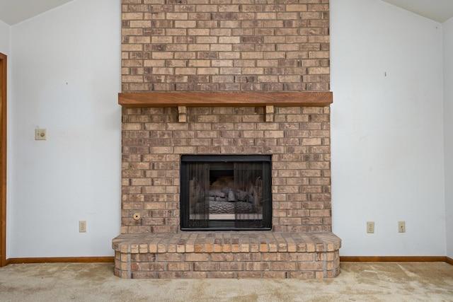 detailed view of carpet flooring, a brick fireplace, and baseboards