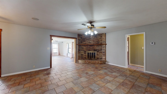 unfurnished living room featuring ceiling fan and a brick fireplace