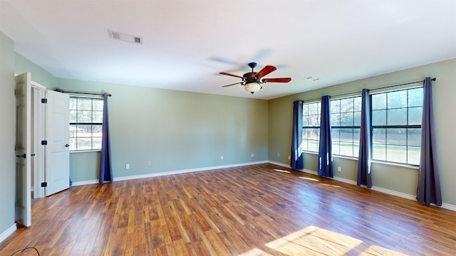 spare room with a wealth of natural light, ceiling fan, and dark hardwood / wood-style floors