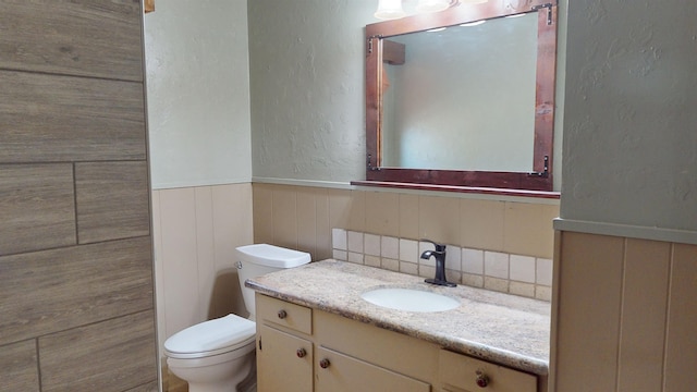 bathroom with vanity, toilet, and backsplash