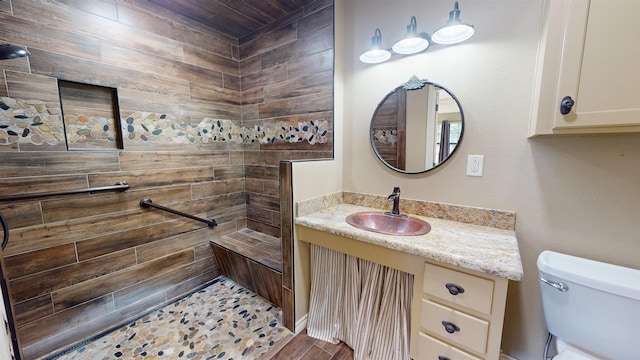 bathroom featuring tiled shower, vanity, and toilet