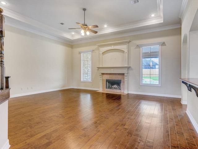 unfurnished living room with ceiling fan, a tray ceiling, dark hardwood / wood-style flooring, and a tile fireplace