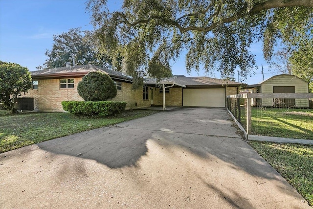 ranch-style house featuring a front lawn, central AC unit, and a garage