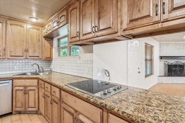 kitchen with light stone countertops, sink, stainless steel dishwasher, electric cooktop, and a fireplace