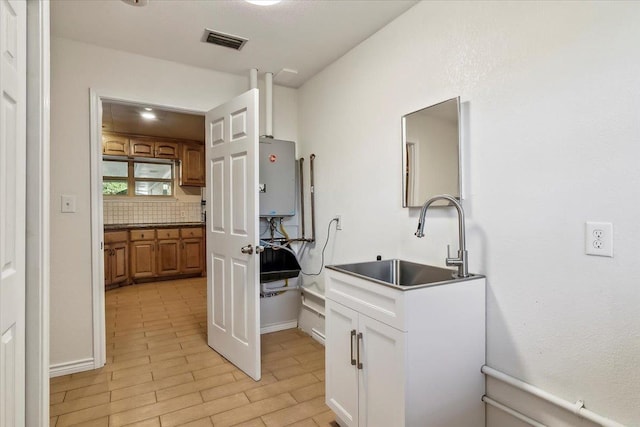 kitchen featuring light wood-type flooring, tasteful backsplash, sink, tankless water heater, and white cabinets