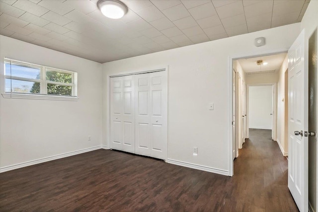 unfurnished bedroom with dark wood-type flooring and a closet