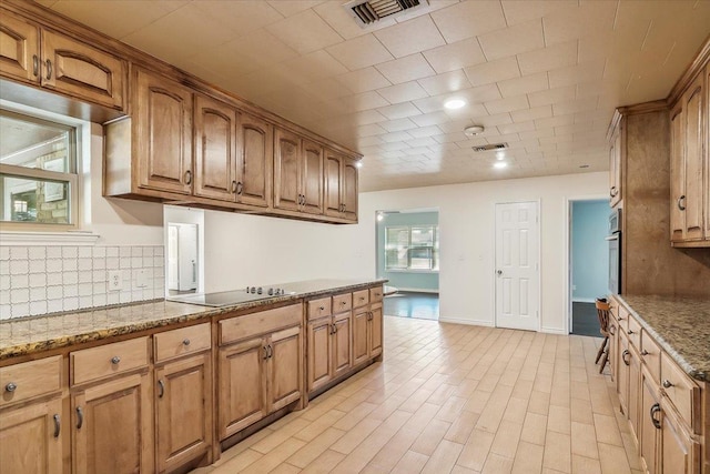 kitchen with electric cooktop, light stone countertops, oven, and decorative backsplash