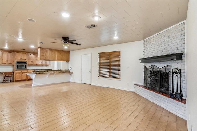 unfurnished living room with light hardwood / wood-style flooring, a brick fireplace, and ceiling fan