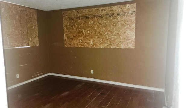 unfurnished room with dark wood-style floors and baseboards