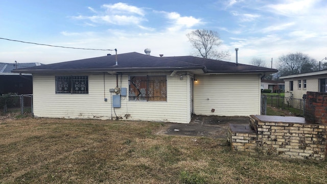 back of property with a lawn and fence