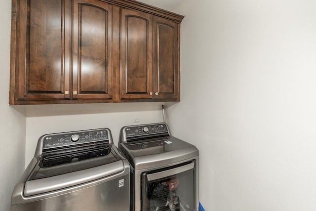 washroom featuring washer and clothes dryer and cabinets