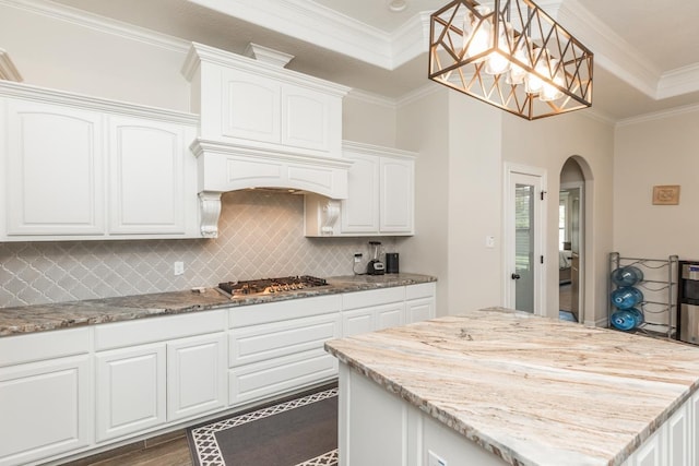 kitchen with crown molding, white cabinets, pendant lighting, and stainless steel gas stovetop