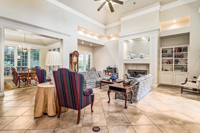 tiled living room with a towering ceiling, built in shelves, and ceiling fan with notable chandelier