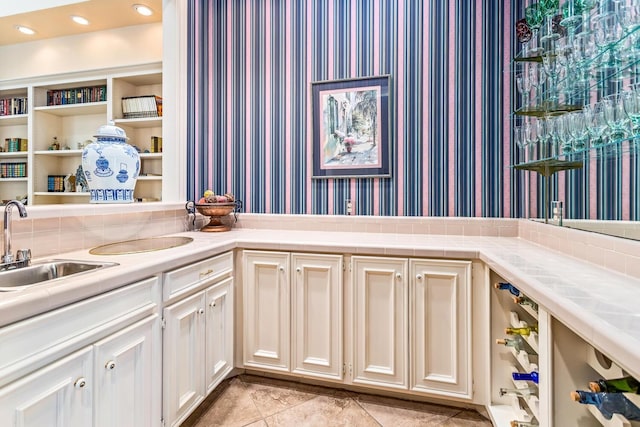 interior space with built in shelves, tile counters, sink, beverage cooler, and light tile patterned floors