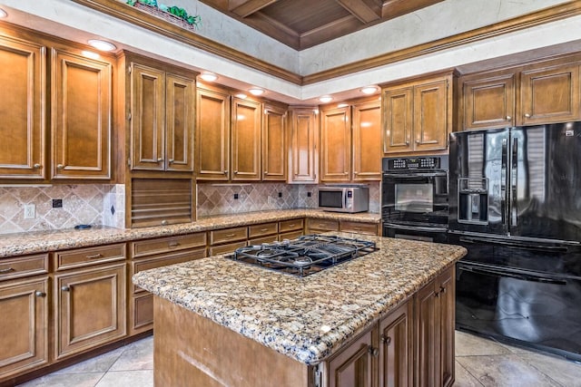 kitchen with black appliances, a kitchen island, light stone countertops, and beamed ceiling