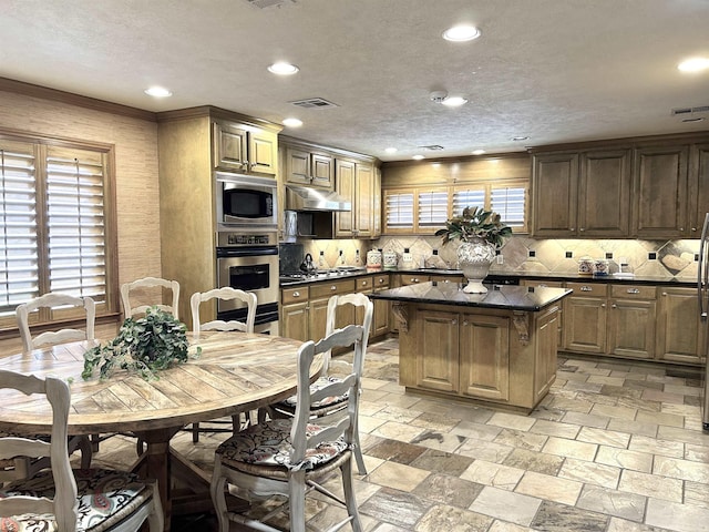 kitchen with a kitchen island, stainless steel appliances, a wealth of natural light, and tasteful backsplash