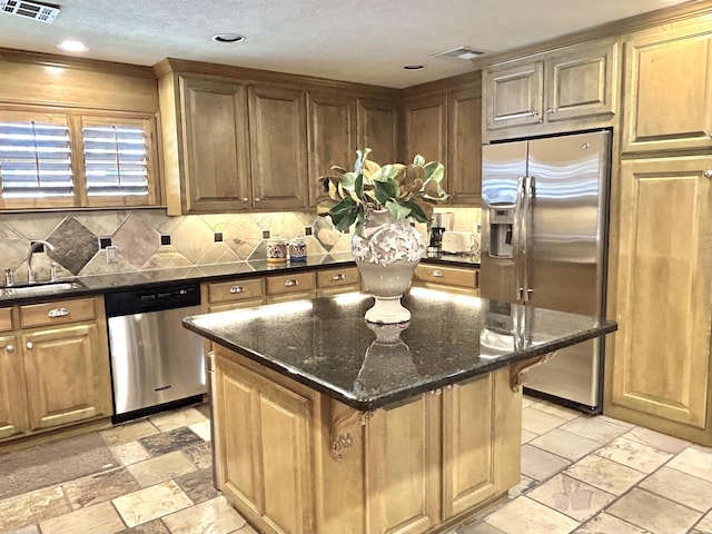 kitchen featuring sink, a center island, stainless steel appliances, tasteful backsplash, and dark stone counters