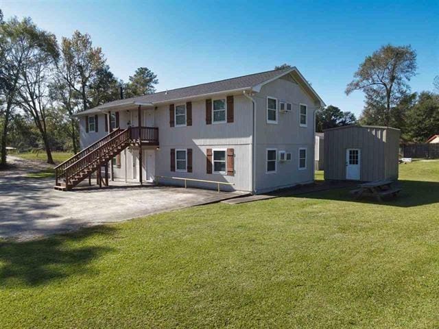 434 US Highway 96, Buna, TX 77612 - back of property featuring a storage shed, an outbuilding, stairway, and a lawn