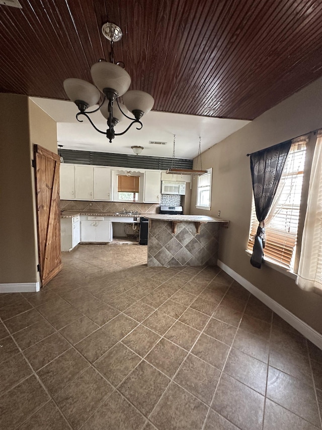 kitchen with pendant lighting, dark tile patterned flooring, white cabinets, decorative backsplash, and kitchen peninsula