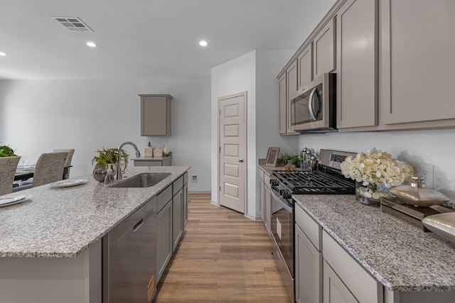 kitchen with a sink, stainless steel appliances, light wood-type flooring, gray cabinets, and recessed lighting