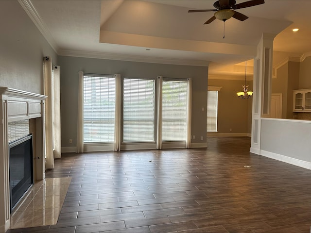 unfurnished living room featuring ceiling fan with notable chandelier, a raised ceiling, crown molding, and a tiled fireplace