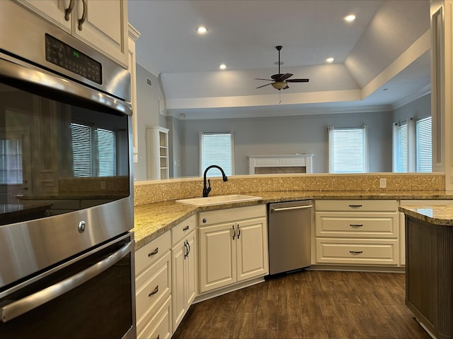 kitchen featuring white cabinets, ceiling fan, sink, and double oven