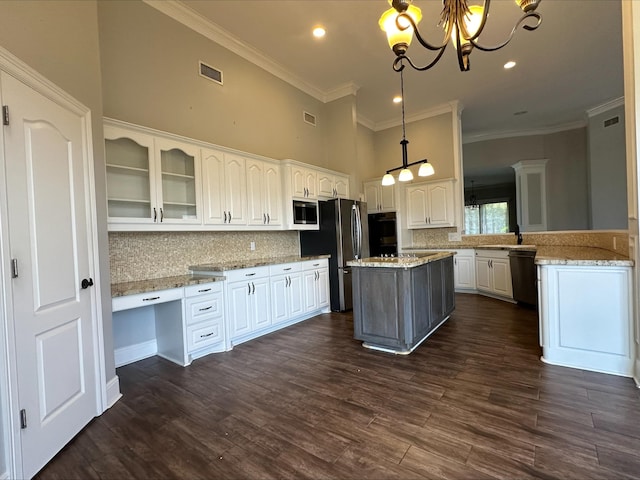 kitchen with a center island, decorative backsplash, appliances with stainless steel finishes, decorative light fixtures, and white cabinetry