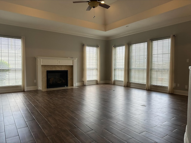 unfurnished living room featuring ceiling fan, a raised ceiling, crown molding, and a tiled fireplace