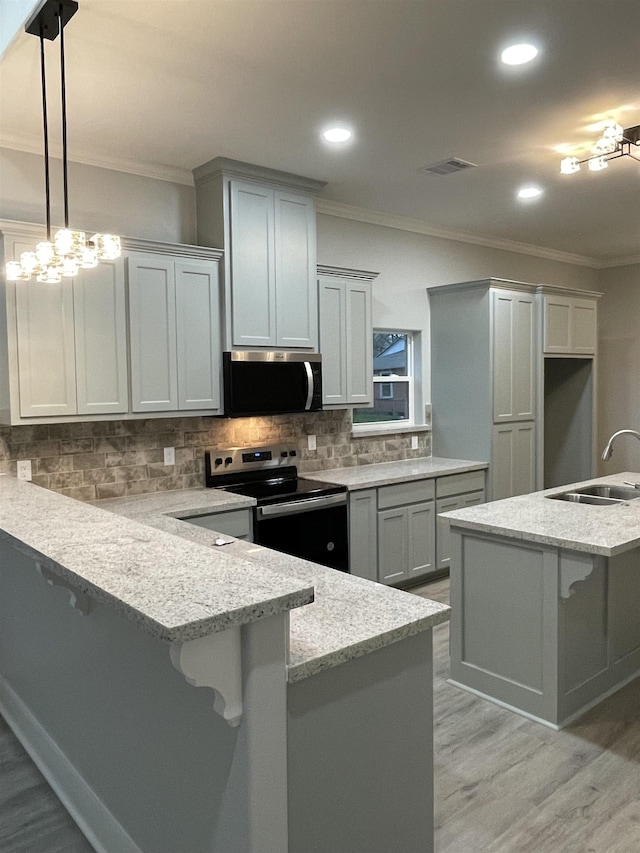 kitchen with crown molding, visible vents, appliances with stainless steel finishes, a sink, and a peninsula