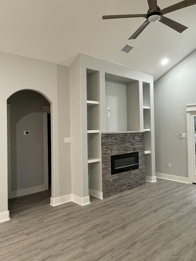 unfurnished living room featuring built in shelves, a fireplace, and wood finished floors