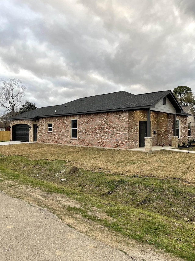 view of front of property featuring a garage, brick siding, and a front yard