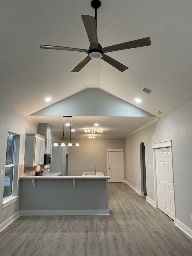 kitchen featuring arched walkways, light countertops, stainless steel microwave, and a kitchen bar