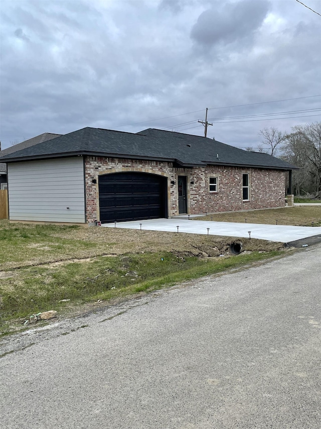 view of front of home featuring a garage, concrete driveway, brick siding, and a shingled roof