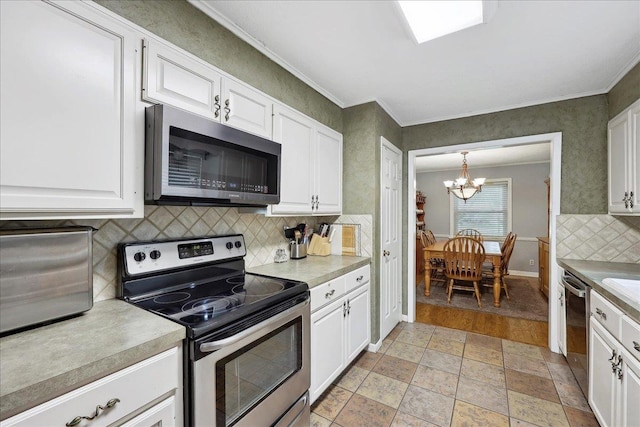kitchen with stainless steel appliances, a notable chandelier, white cabinetry, and tasteful backsplash
