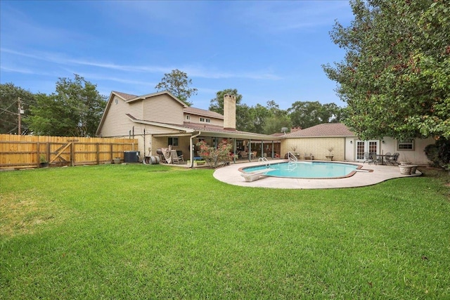 view of pool with french doors, a lawn, a patio area, cooling unit, and a fenced backyard