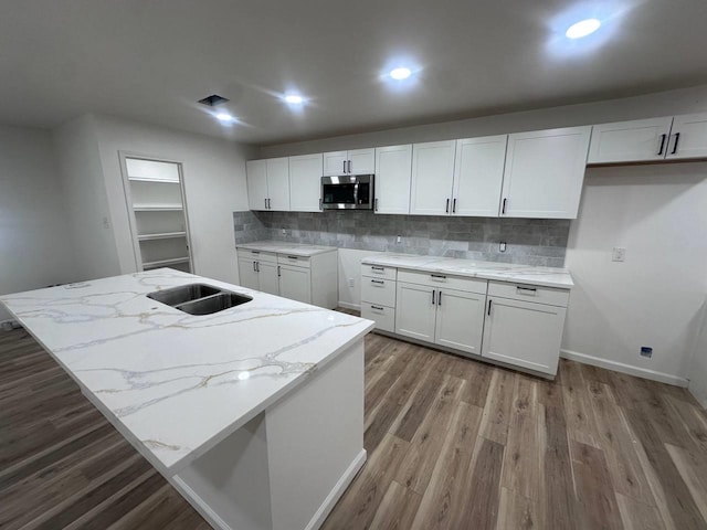1117 W Dr, Port Neches, TX 77651 - kitchen with stainless steel microwave, a sink, wood finished floors, light stone counters, and recessed lighting