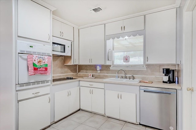 kitchen with white appliances, backsplash, white cabinets, sink, and light tile patterned flooring