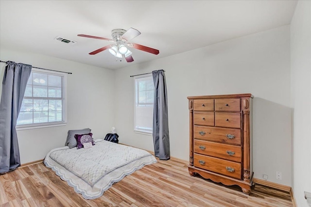 bedroom featuring ceiling fan, light wood-type flooring, and multiple windows