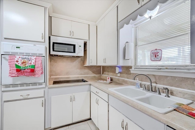 kitchen featuring light tile patterned floors, white appliances, white cabinetry, and sink