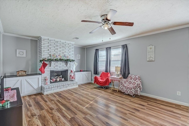 living area featuring hardwood / wood-style floors, a textured ceiling, a brick fireplace, and ornamental molding