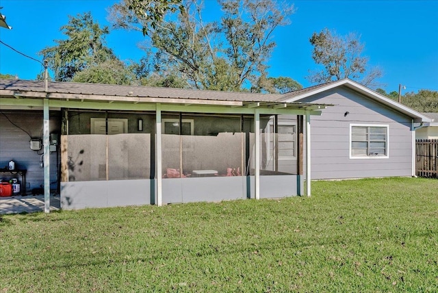 rear view of property featuring a sunroom and a yard