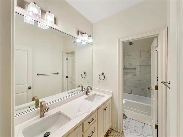 full bath featuring double vanity, toilet, marble finish floor, and a sink